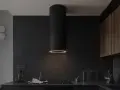 Nowoczesny okap kuchenny czarny z pierścieniem świetlnym nad płytą indukcyjną. W tle ciemne, kamienne ściany i drewniane szafki.