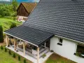 Nowy, ciemny dach z dachówki nad tarasem. Dowiedz się, jak naprawić dach z dachówki, by służył latami.