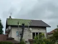 Remont dachu domu: połowa pokryta zieloną łacą, połowa brązową dachówką, rusztowanie.
