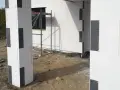 Budowa domu z bloczków styropianowych. Czy trzeba kołkować styropian grafitowy? Widok na fragment ściany i słupa z szarego styropianu.