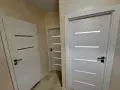 Nowoczesne drzwi Drea Auri w białym kolorze, z eleganckimi, poziomymi przeszkleniami, tworzą stylowe przejście w korytarzu.