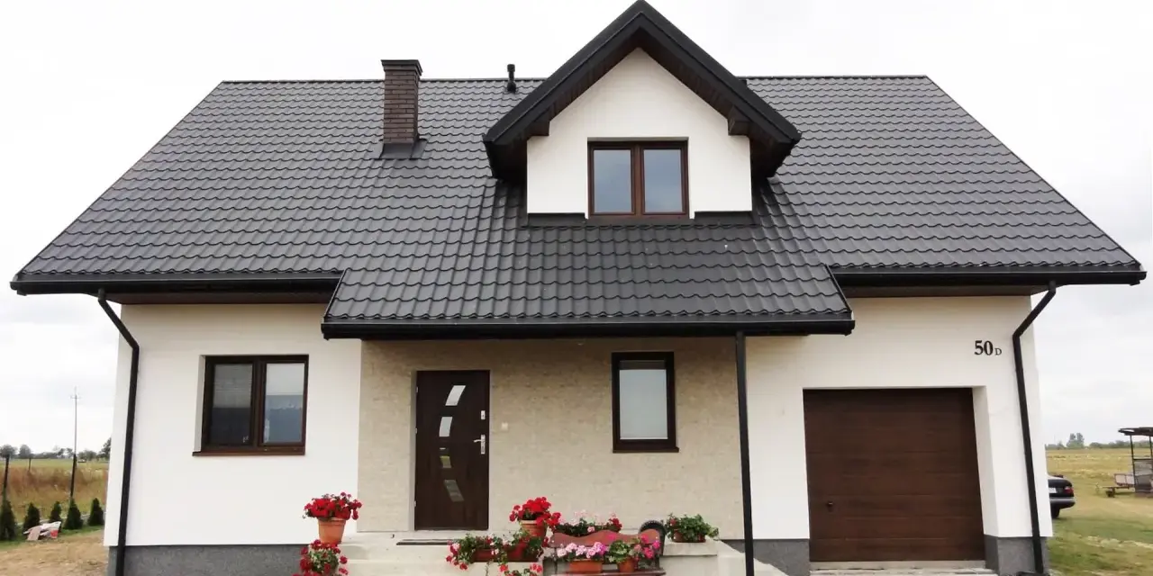 Nowy dom z brązowym dachem i białymi oknami. Elewacja częściowo jasna, częściowo z kamienia.