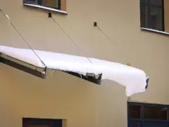 Zimowy daszek nad drzwiami, obciążony śniegiem i lodem, pokazuje, jak zrobić daszek nad drzwi, który ochroni przed zimnem.