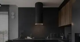Nowoczesny okap kuchenny czarny z pierścieniem świetlnym nad płytą indukcyjną. W tle ciemne, kamienne ściany i drewniane szafki.